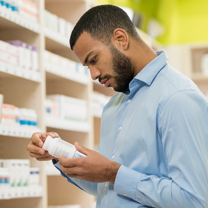 Man looking at a bottle of supplements