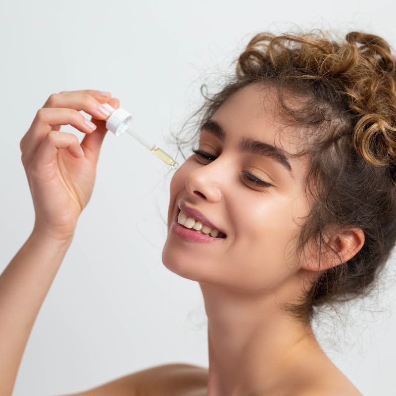 Woman applies serum to cheek with dropper