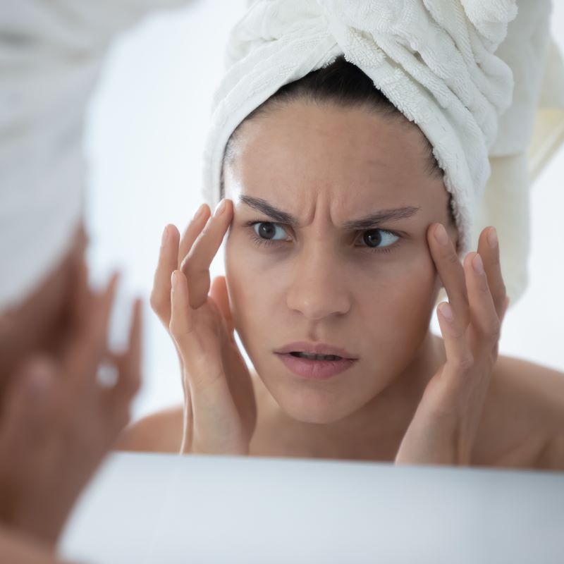 worried woman looks in mirror at face worried woman looks in mirror at face