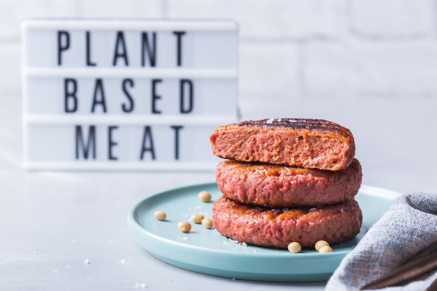 three patties stacked in front of sign saying plant based three patties stacked in front of sign saying plant based
