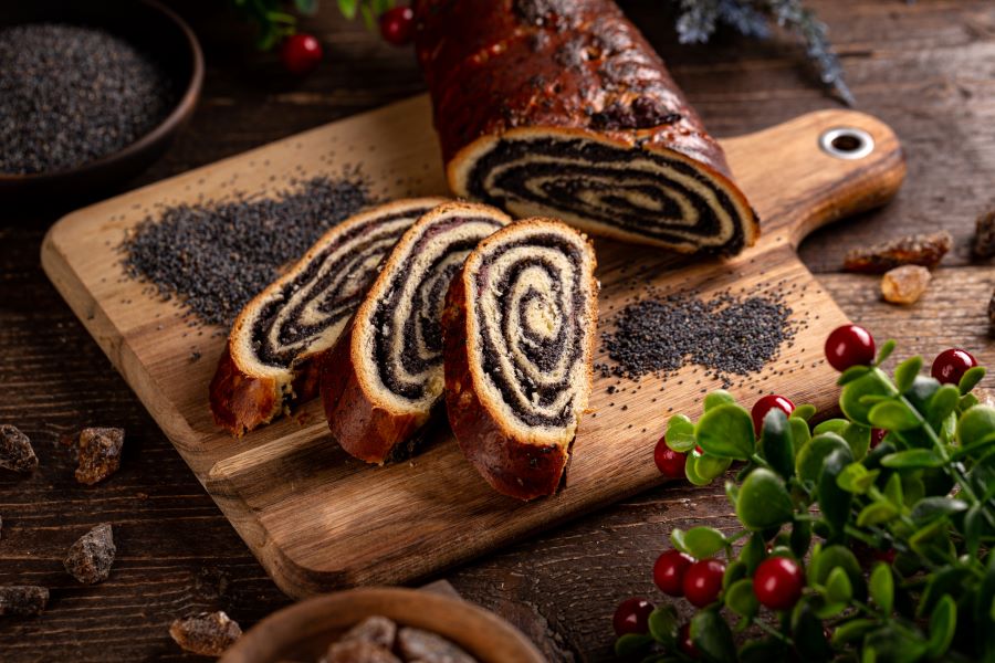 Rolled bread full of poppy seeds on cutting board and surrounded by piles of poppy seeds. Rolled bread full of poppy seeds on cutting board and surrounded by piles of poppy seeds.