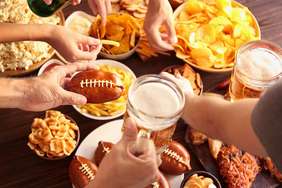 People eating several unhealthy snacks and drinking beers while watching the Super Bowl. People eating several unhealthy snacks and drinking beers while watching the Super Bowl.