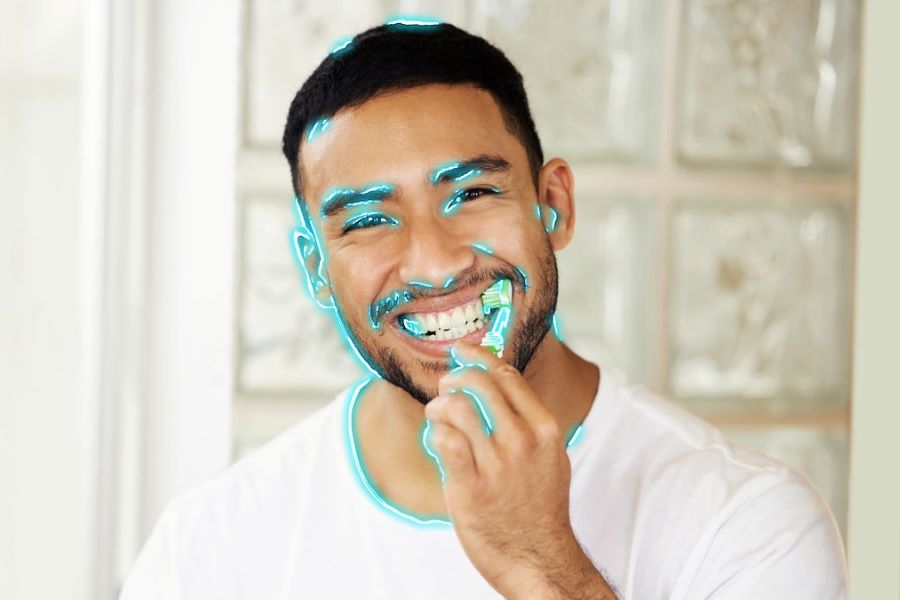 A man brushing his teeth with blue neon lines drawn around his face.