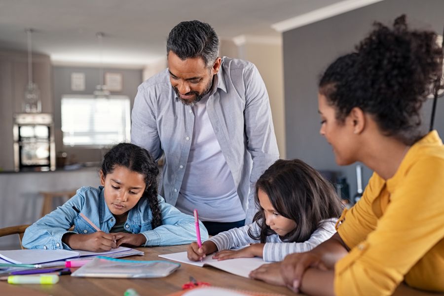 Parents help their adolescent children do their homework at the kitchen table.