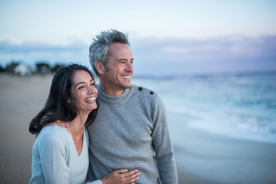 A very happy and satisfied looking older couple stare at the horizon on the beach while smiling. A very happy and satisfied looking older couple stare at the horizon on the beach while smiling.