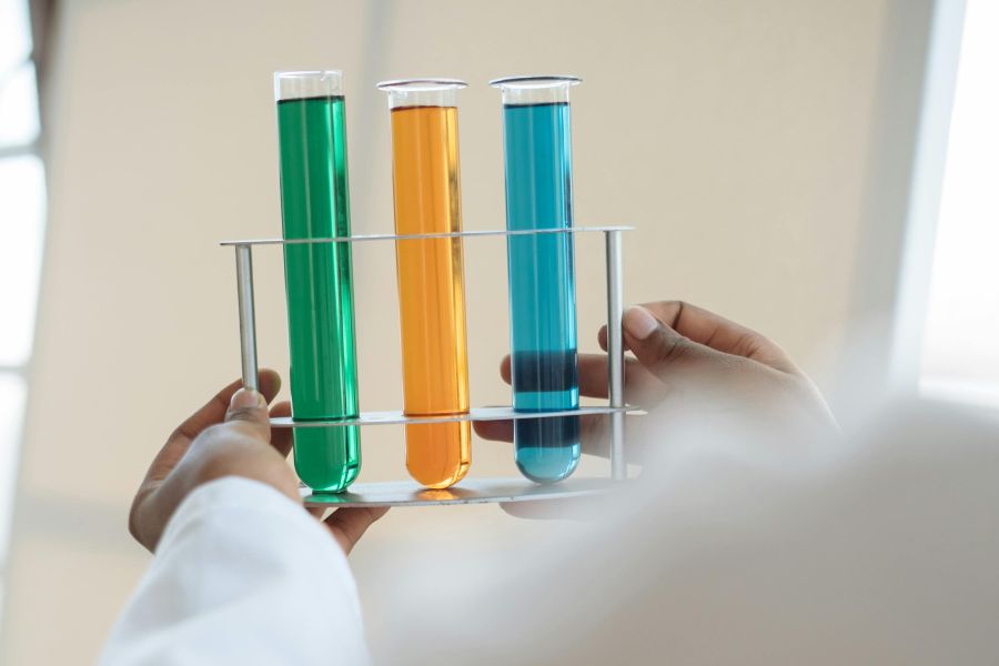 Hands holding three test tubes with liquids of different colors. Hands holding three test tubes with liquids of different colors.