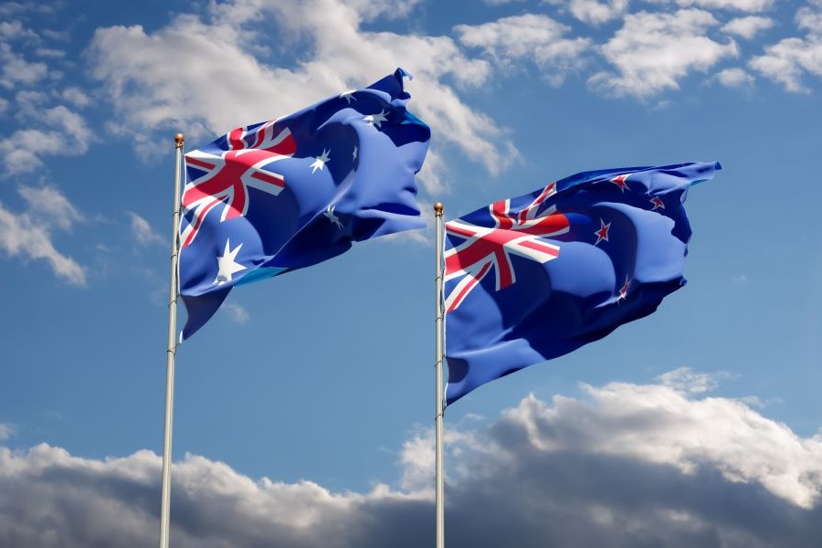 Australia and New Zealand's flags flying side by side on poles on a clear and sunny day. Australia and New Zealand's flags flying side by side on poles on a clear and sunny day.