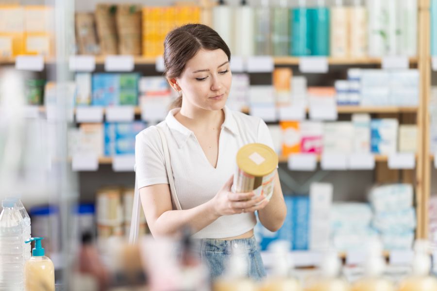 A woman reads the label on a supplement in a health food store.