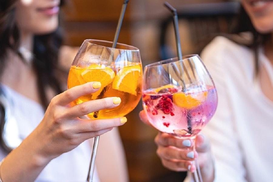 two women's hands holding wine glasses with colored liquids two women's hands holding wine glasses with colored liquids
