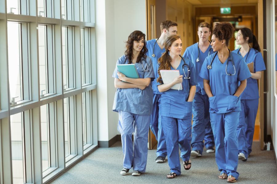 med students in uniform walk in corridor chatting