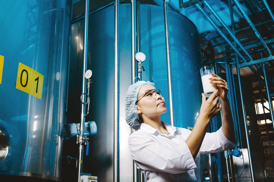 female scientist looking at a beaker of milk inside a factory