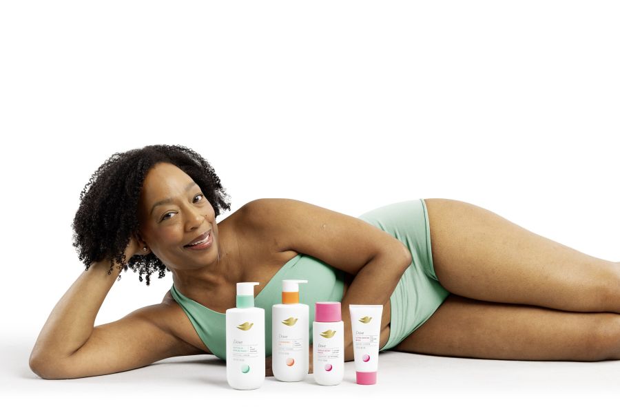 A woman lying down with Dove body products in front of her.