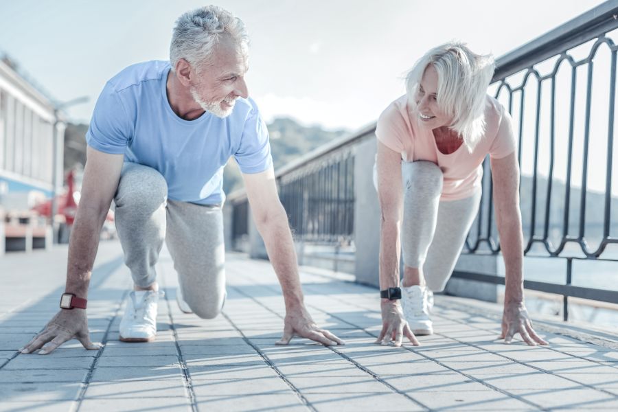 An older couple prepare to sprint against each other on a bridge. An older couple prepare to sprint against each other on a bridge.