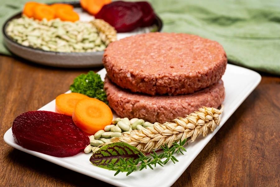 plant based meat patty on white plate next to beetroot and carrot slices plant based meat patty on white plate next to beetroot and carrot slices