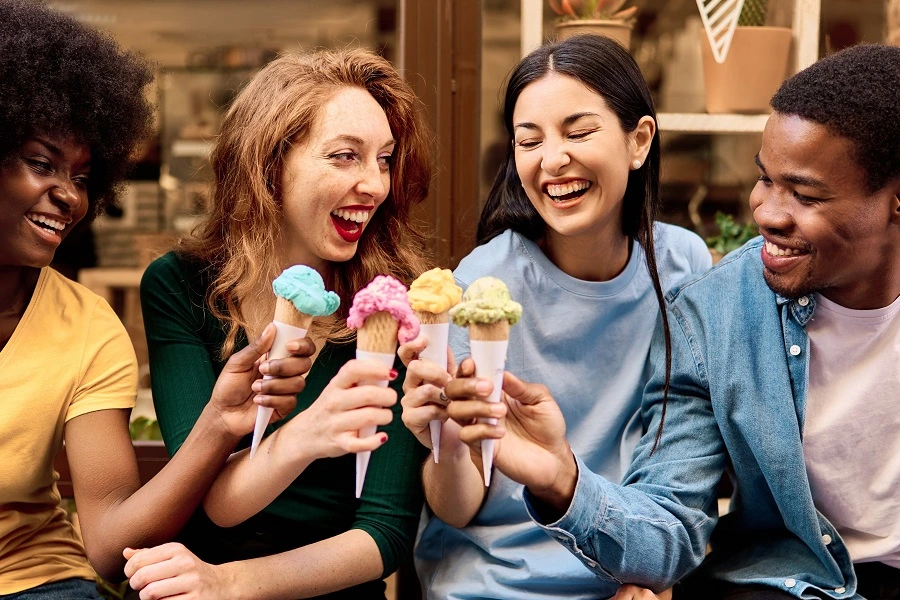 four young multi ethnic friends eating colorful ice creams