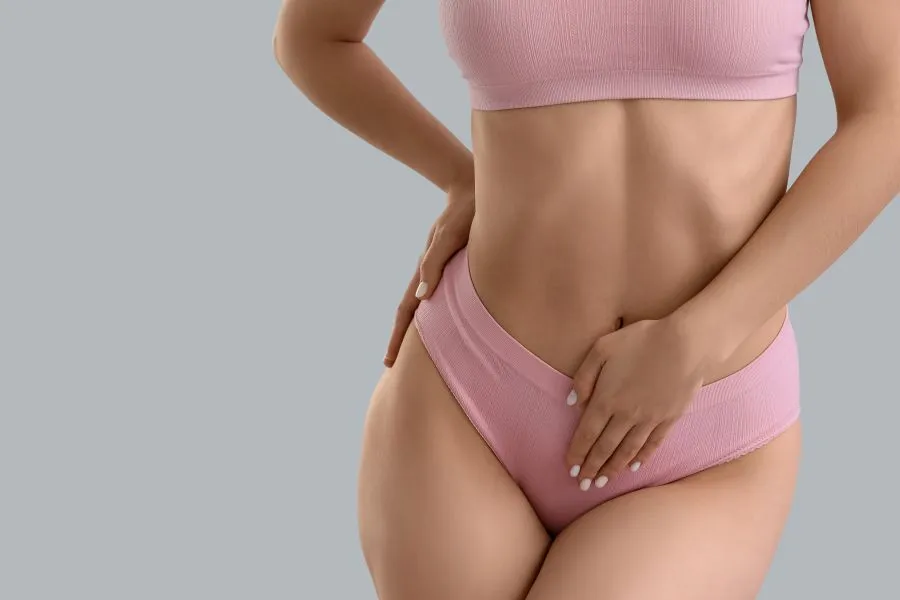 A woman wearing a pink underwear and bra set and putting her hand on her stomach. A woman wearing a pink underwear and bra set and putting her hand on her stomach.