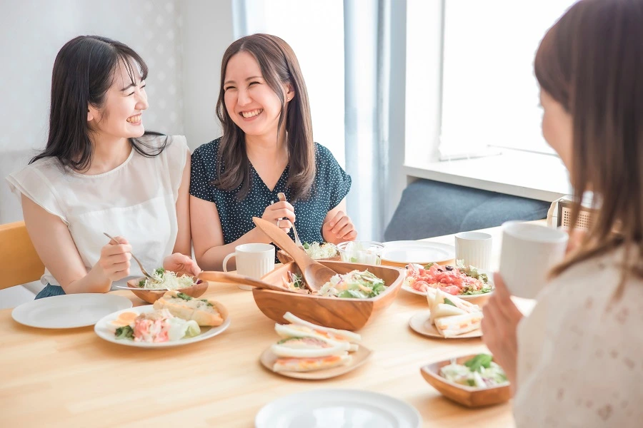 three Asian women eating food and smiling