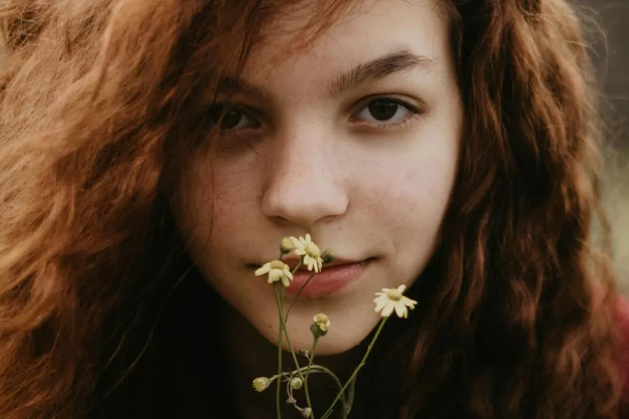 A girl with a flower over her mouth. A girl with a flower over her mouth.