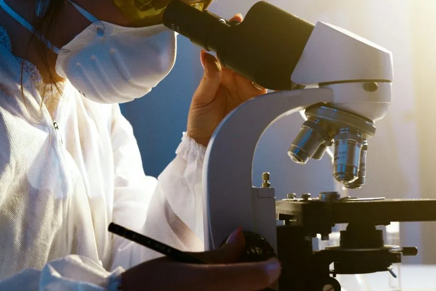 A scientist looking into a microscope in a lab setting A scientist looking into a microscope in a lab setting