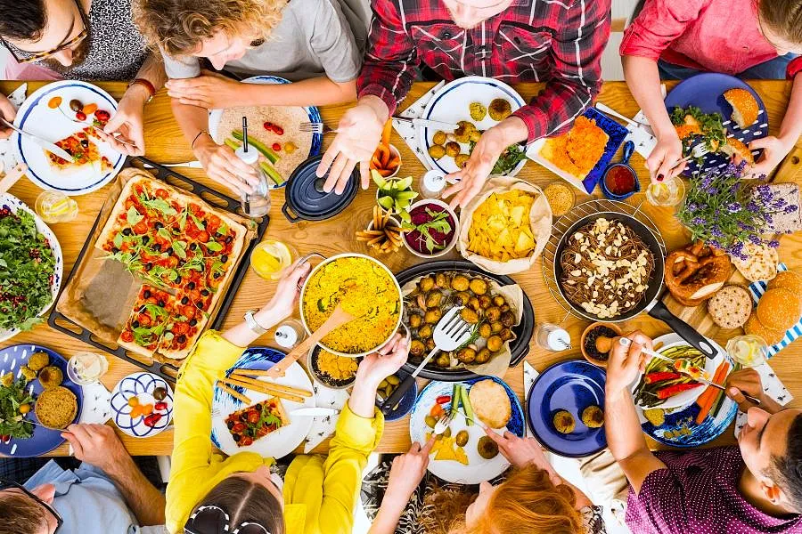 People at a table with lots of colorful foods.