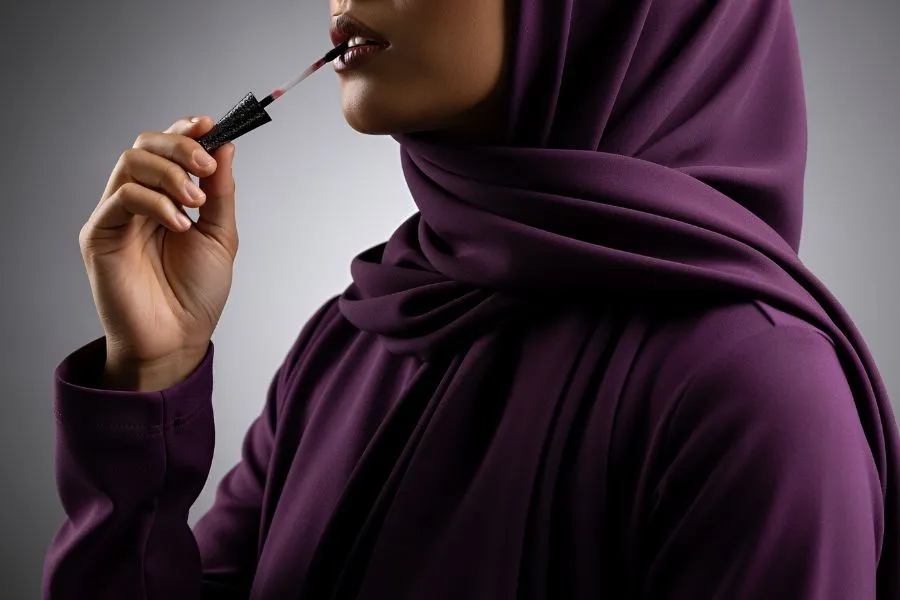 Woman wearing a hijab applying lipstick