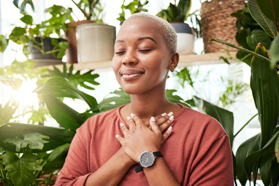 young woman by plants looking peaceful with eyes closed young woman by plants looking peaceful with eyes closed
