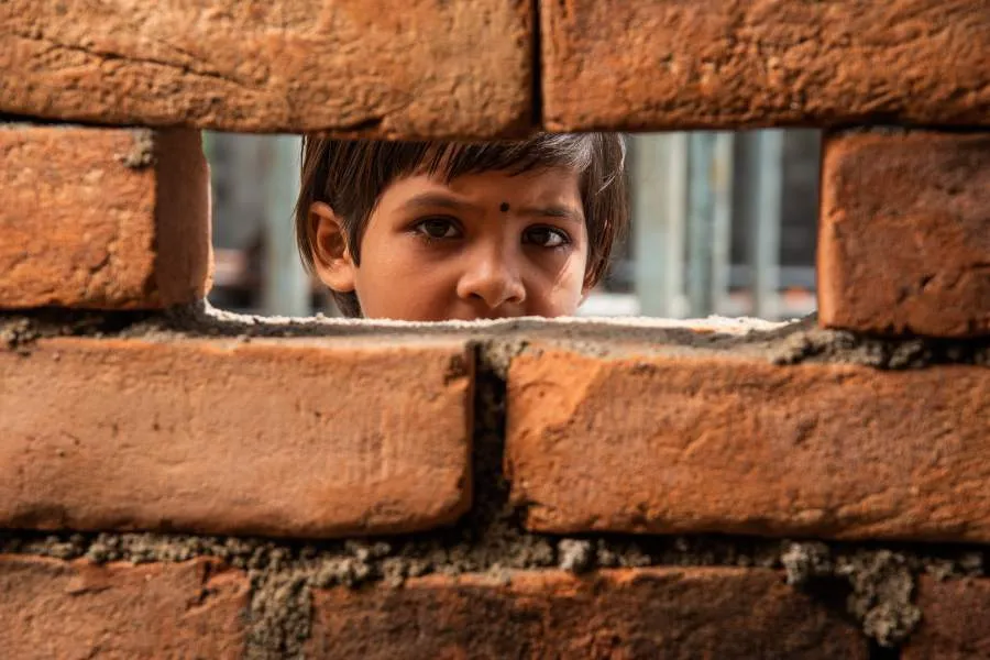 Image child in india looking through stone wall