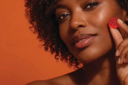Image A woman holding a gummy that looks like a raspberry.