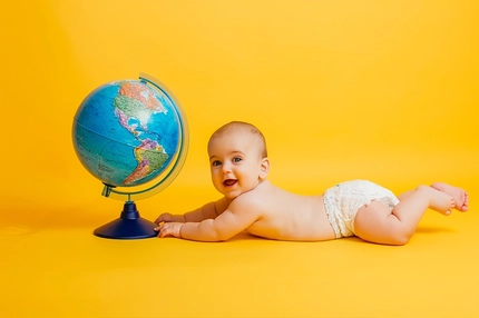 Image baby playing with globe on yellow background