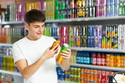 Image teenage boy with energy drink can in supermarket
