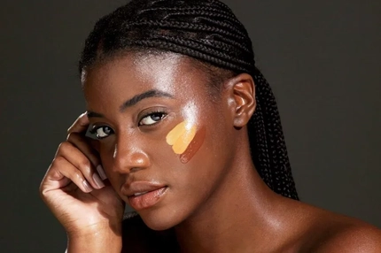 A Black woman with three foundation swatches on her cheek.