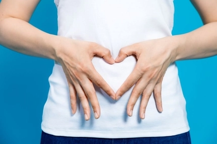 Image woman who makes a heart shape by hands on her stomach