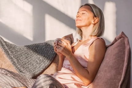 A woman smiling and holding a cup of tea.