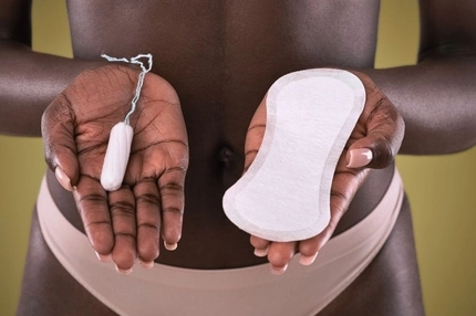 person holds a tampon and a daily pad in open palms