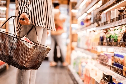 woman's hand holding basket inside supermarket