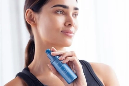 A woman holding a bottle of Firmwear serum.
