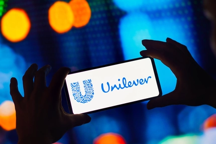 Image Hands holding a phone that says Unilever on it.