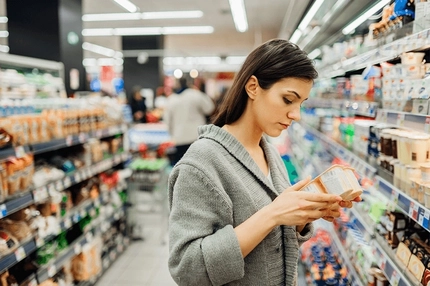 woman checking food label in supermarket