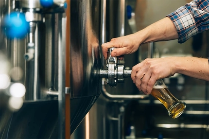 Worker pouring beer at brewery.