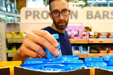 man picking up protein bar from supermarket aisle