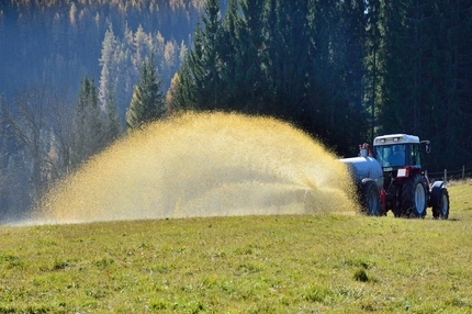 Tractor spraying fertilizer over a field.