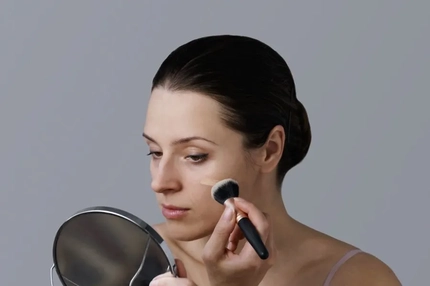 Image A woman blending makeup on her cheek.