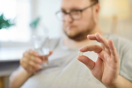 An obese man gets ready to take a pill.