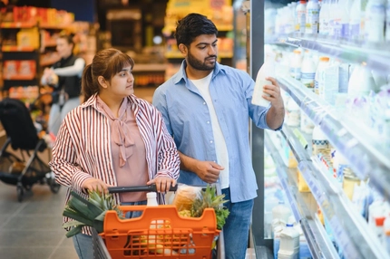Couple shop for dairy products in the grocery store.