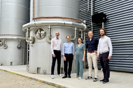 Image people standing in front of large bioreactor