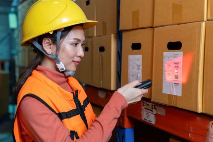 Image A person wearing a hard hat and safety vest scanning a bar code