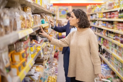 Image A woman peruses the baked goods aisle in a grocery store.