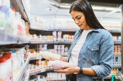young woman in supermarket holding two bottles