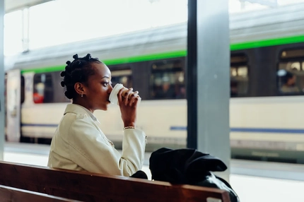 Image woman drinks coffee waiting for train