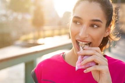 Image Woman outdoors next to river eats snack